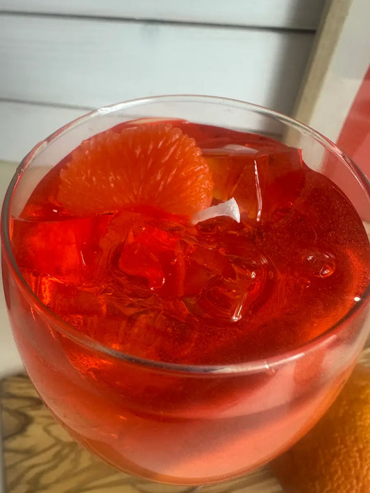 Detailaufnahme der handgegossenen Duftkerze Aperol Spritz mit Orangenscheibe und Eiswürfeln – kramMITcharme