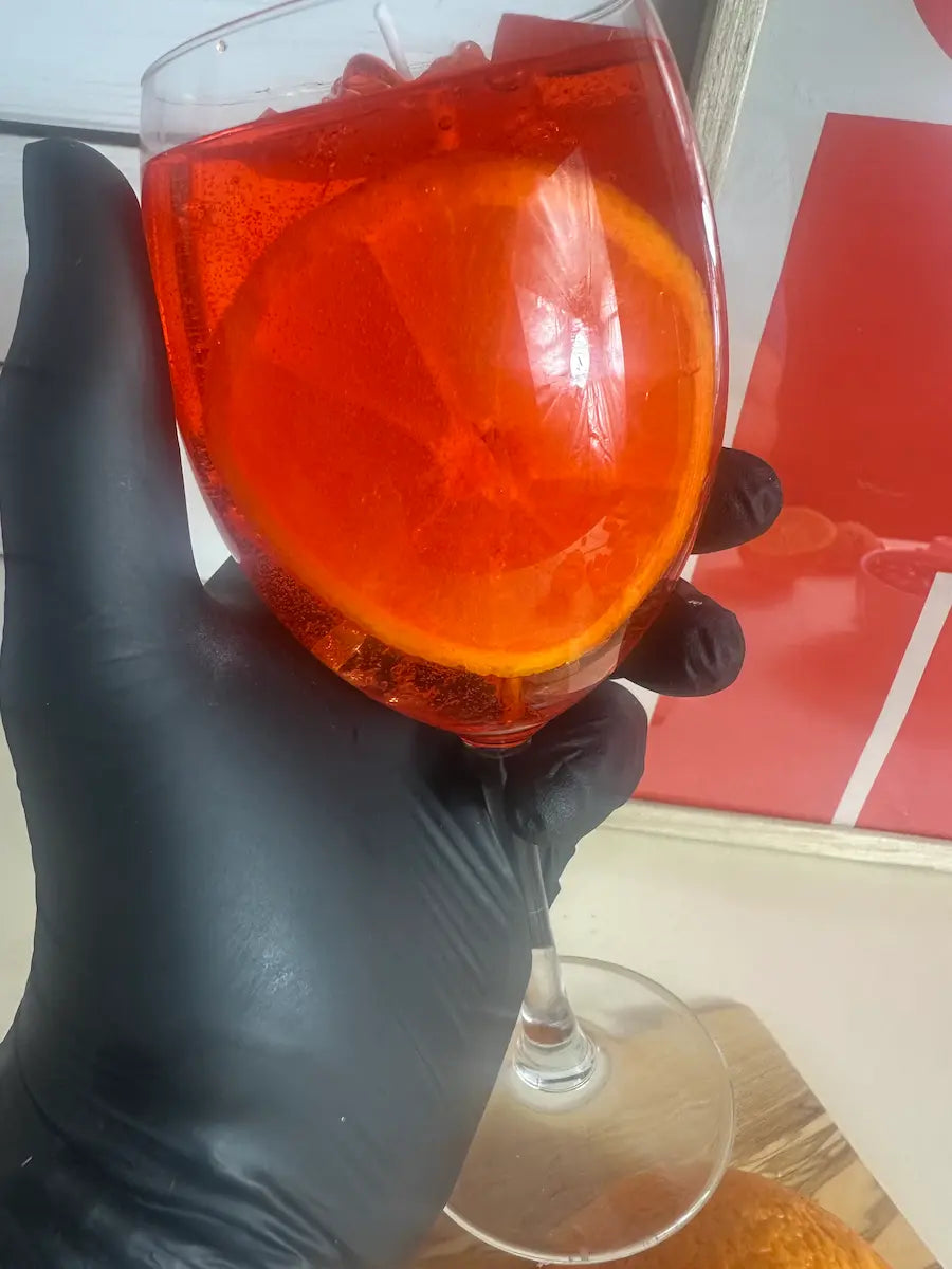 Handaufnahme der Duftkerze Aperol Spritz – handgegossen mit Orangenscheibe und Glasdetail – kramMITcharme