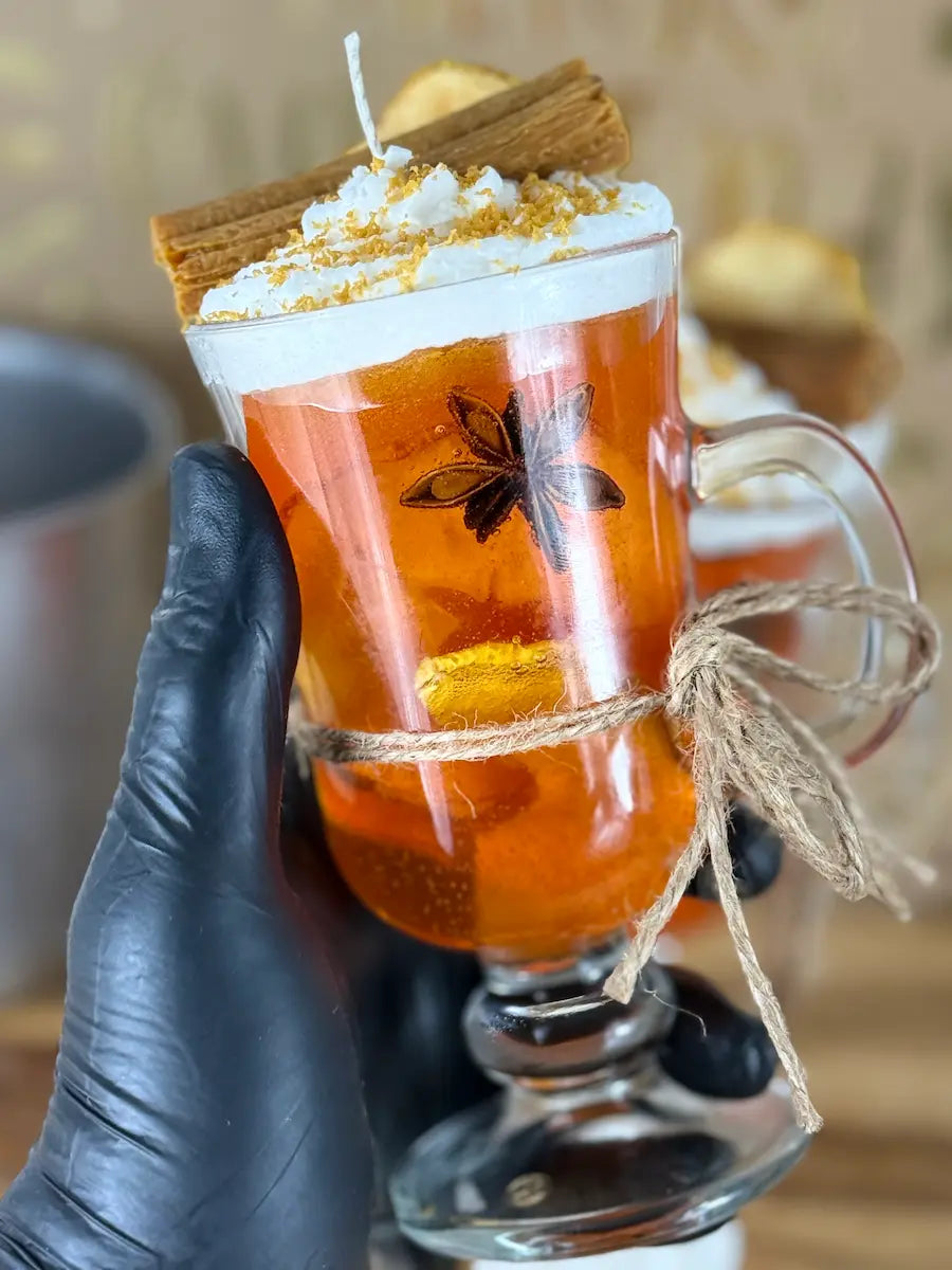 Handaufnahme der Duftkerze Apfelzauber im Glas mit Sternanis, Zimt und Apfelscheibe – kramMITcharme