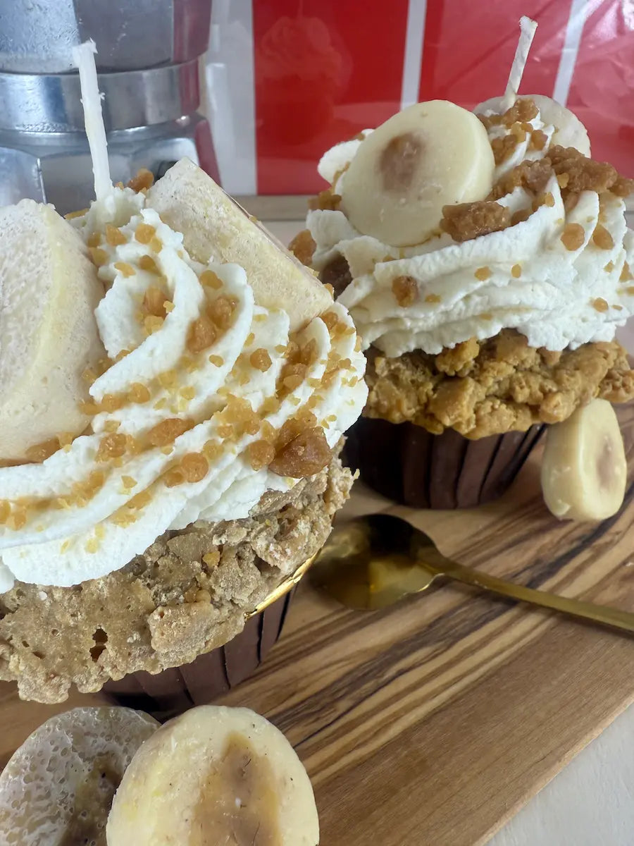 Seitenansicht der Banana Swirl Cupcake Duftkerze mit Karamellstreifen und Banane auf Holzbrett – kramMITcharme