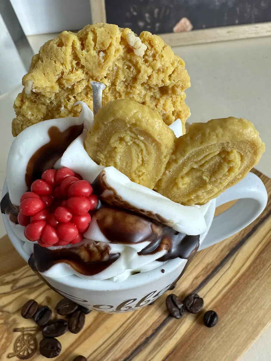 Detailaufnahme der Duftkerze „Coffee Makes Everything Possible“ mit roten Beeren und Schokosoße – kramMITcharme