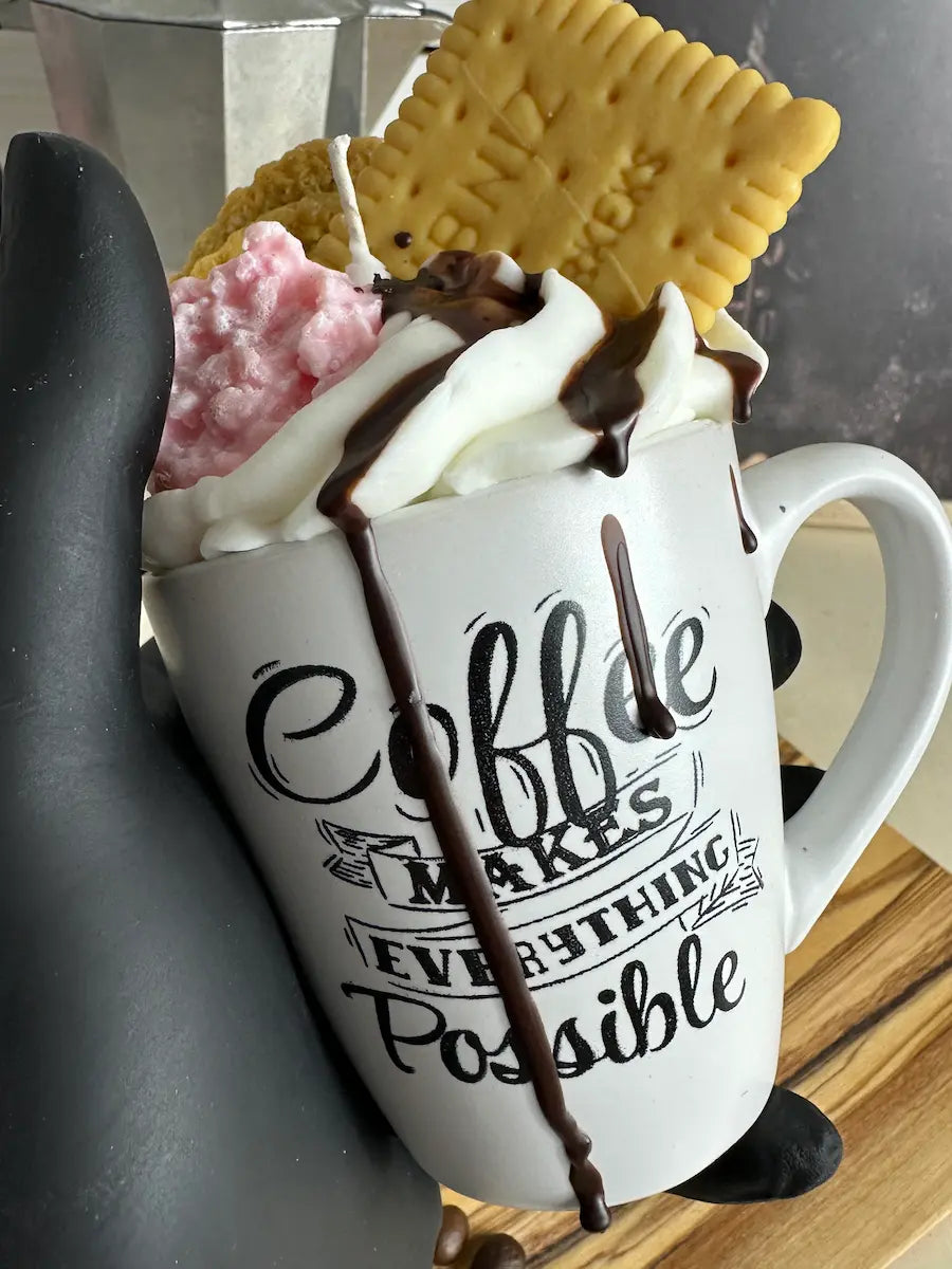 Handaufnahme der Duftkerze „Coffee Makes Everything Possible“ mit cremigem Wachs und Gebäck-Topping – kramMITcharme