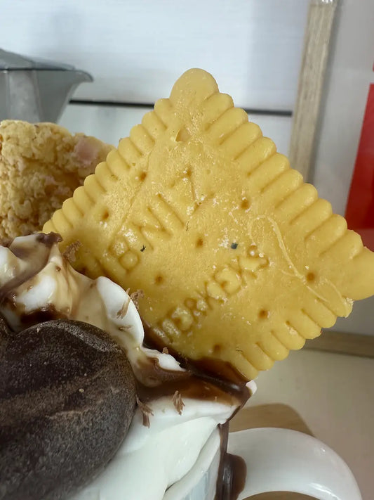 Detailaufnahme der Duftkerze „Einsteins Coffeecup“ mit Keks und cremiger Wachsstruktur – kramMITcharme