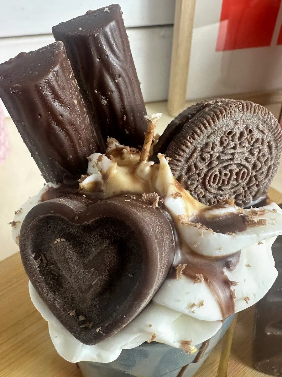 Detailaufnahme der Duftkerze „Little Blue Coffee Cup“ mit Herzstück aus Schokowachs und cremigem Topping – kramMITcharme