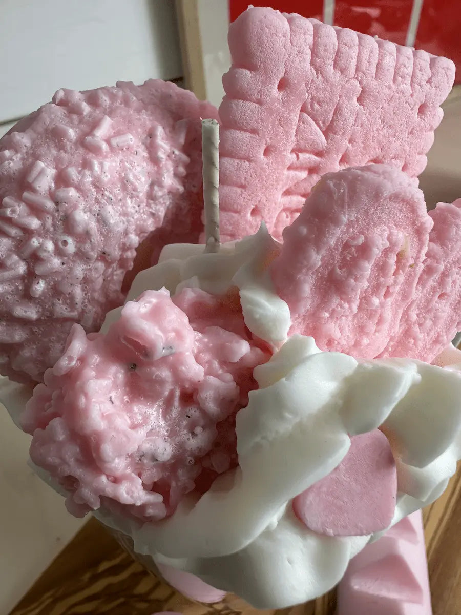 Nahaufnahme der Duftkerze „Beste Mama der Welt“ mit rosa Gebäck und weißem Sahnetopping – kramMITcharme