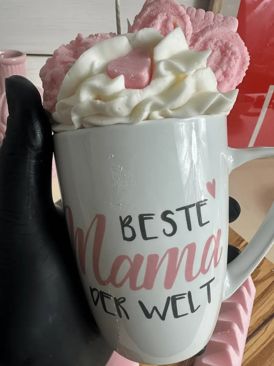 Handaufnahme der Tassenkerze „Beste Mama der Welt“ mit cremigem Wachs-Topping und Deko – kramMITcharme