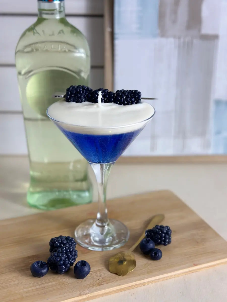 Handgemachte Duftkerze Blueberry Martini im Cocktailglas mit blauer Basis und cremigem weißen Topping – kramMITcharme
