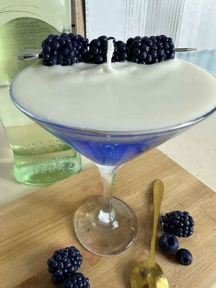 Seitenansicht der Duftkerze Blueberry Martini mit Blaubeer-Deko auf Holzunterlage – kramMITcharme