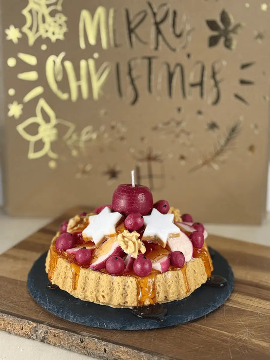 Handgemachte Duftkerze „Bratapfel Royale“ als winterliche Tarte mit Apfelkerze, roten Beeren, weißen Sternen und Karamelloptik auf Holzbrett – kramMITcharme