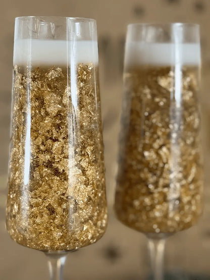 Nahaufnahme der goldglitzernden Dessertkerze im eleganten Champagnerglas vor festlichem Hintergrund – kramMITcharme