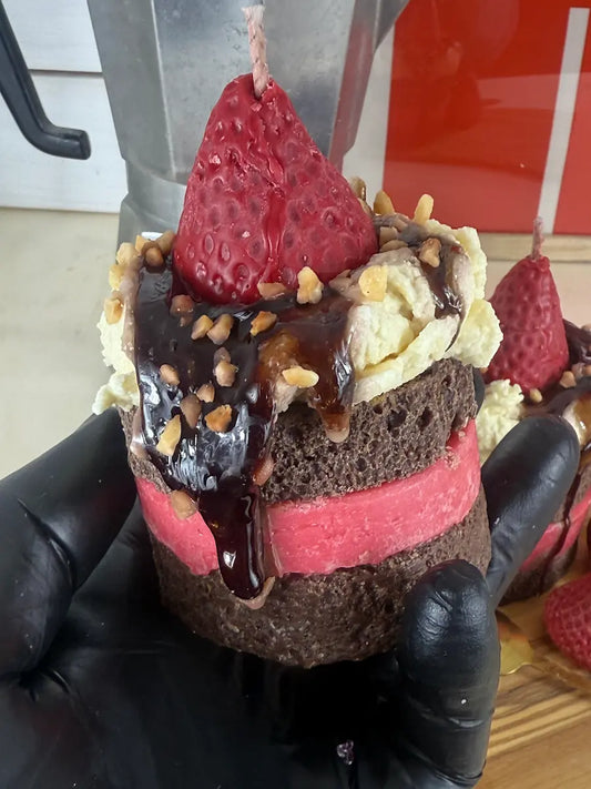 Handaufnahme der Duftkerze ChocoBerry Bite Cake mit Schokoglasur und Erdbeer-Topping – kramMITcharme