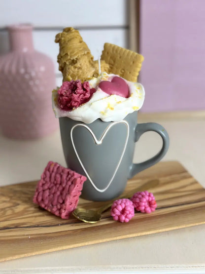 Schrägaufnahme der Duftkerze „Coffee of Love“ mit rosa Deko und Keksen auf Holzplatte – kramMITcharme