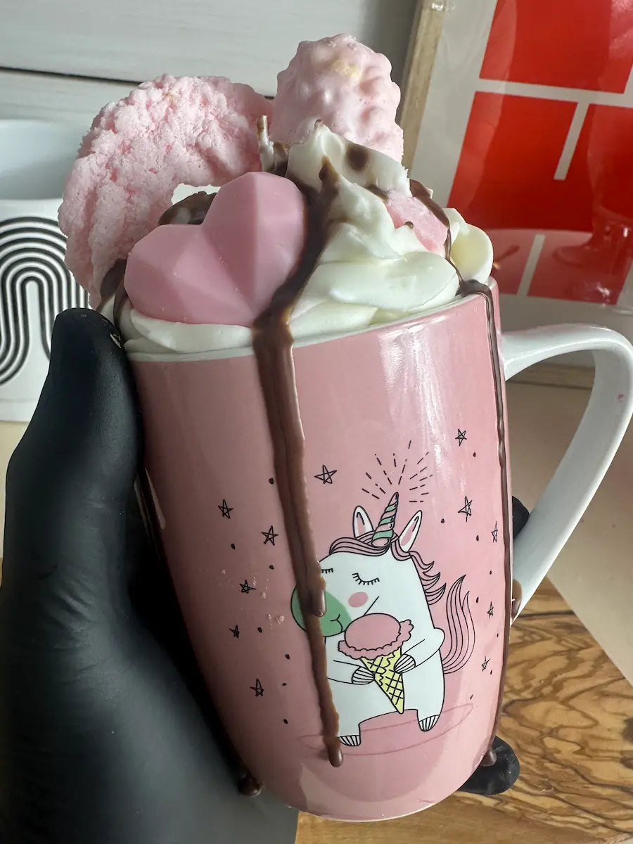 Handaufnahme der Duftkerze „Einhorn“ mit Tassenmotiv und cremiger Wachsdekoration – kramMITcharme