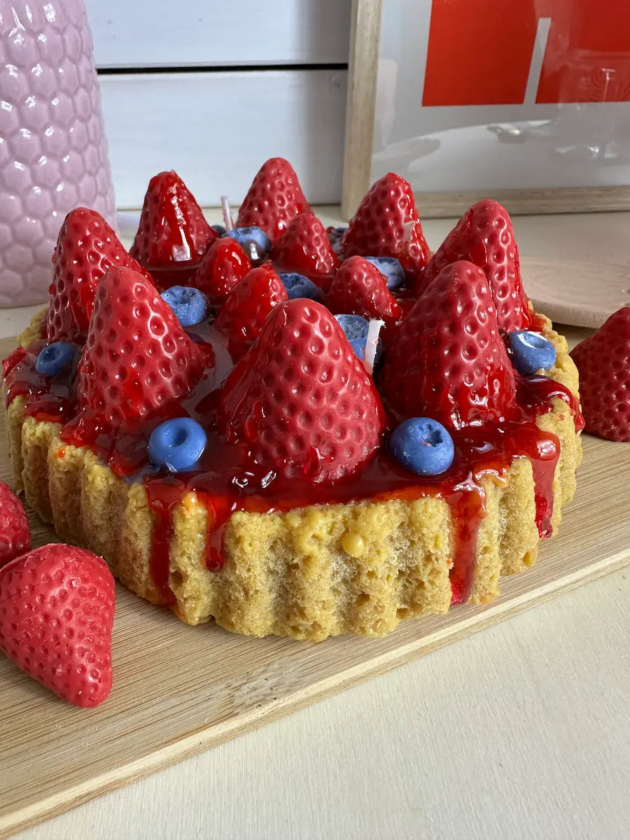 Seitenansicht der Duftkerze „Erdbeerkuchen“ mit tropfender roter Wachs-Glasur und Früchten – kramMITcharme