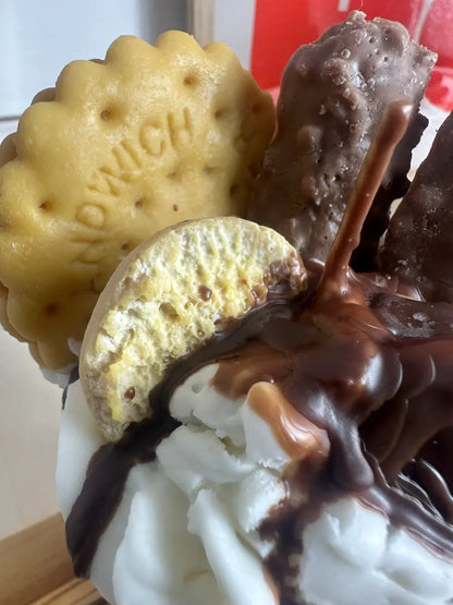 Nahaufnahme der Duftkerze „First Coffee“ mit geschmolzener Schokosoße und Gebäckdeko – kramMITcharme