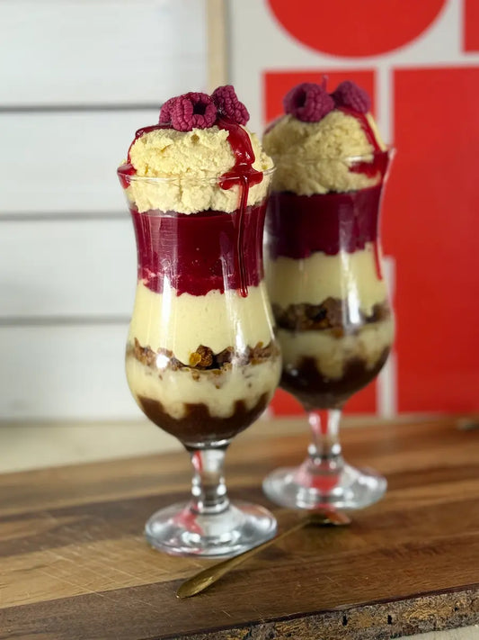 Handgemachte Dessertkerze im Glas mit Vanillecreme-Optik, Himbeerschichten und Keksboden – kramMITcharme