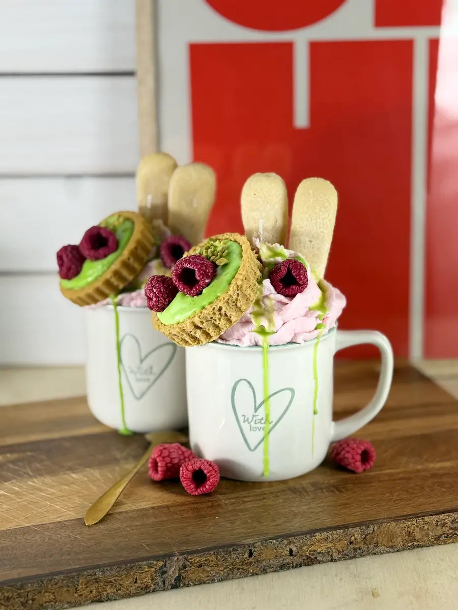 Handgemachte Dessertkerze in Kaffeetasse mit rosafarbener Sahneoptik, Pistaziencreme und Himbeer-Topping – kramMITcharme