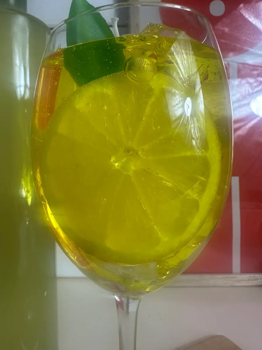Detailaufnahme der handgegossenen Duftkerze „Limoncello Spritz“ mit gelbem Wachs und Zitrusdeko – kramMITcharme