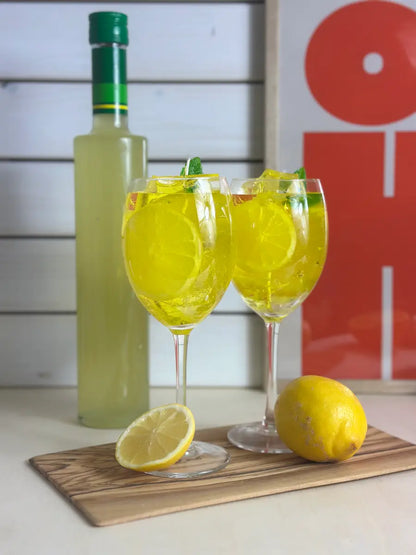 Handgemachte Duftkerze „Limoncello Spritz“ im Weinglas mit gelbem Wachs, Eiswürfeloptik und Zitronenscheibe – kramMITcharme
