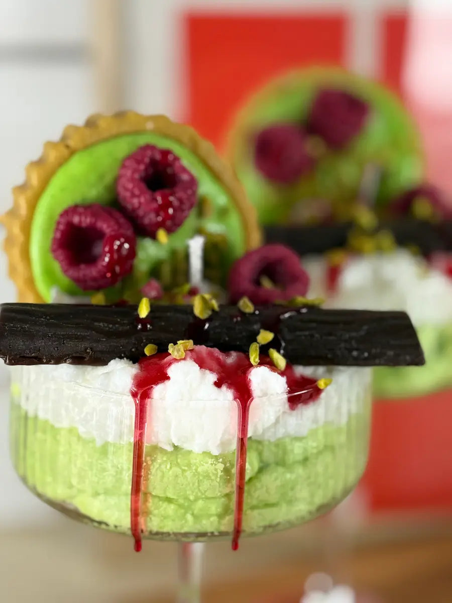 Handgemachte Dessertkerze im Glas mit grüner Pistazienoptik, Himbeersauce und Schoko-Akzenten – kramMITcharme