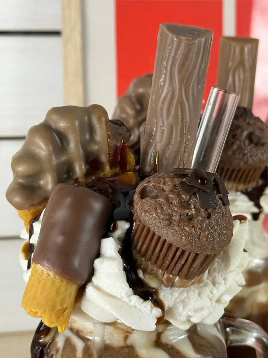 Nahaufnahme der luxuriösen Dessertkerze mit Schokoriegeln, Mini-Muffin und Sahneoptik – kramMITcharme